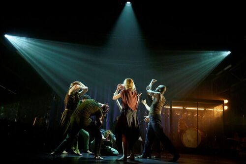 An ensemble of dancers in movement on stage