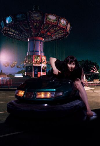 A figure in movement out of a dodgem car on a backdrop of a fairground