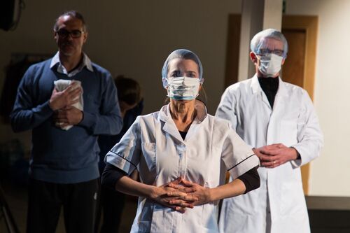 Participants costumed in medical uniforms and face masks with hands clasped at their front