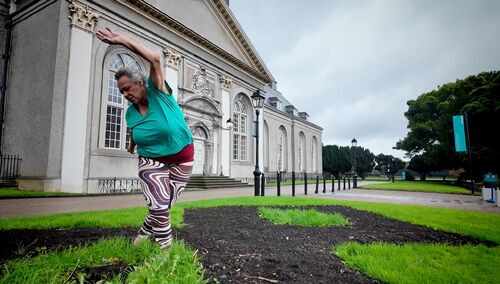 A woman in a movement on the ground with a grass