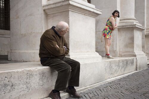 A fleeting glance between a man and a woman among the columns