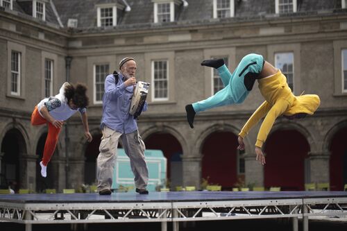 A still of two dancers breakdancing with a figure playing bodhrán between them