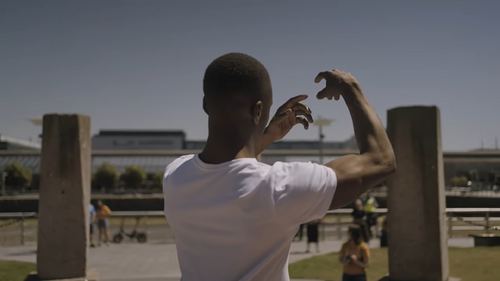 A back of a dancer moving his arms in front of him