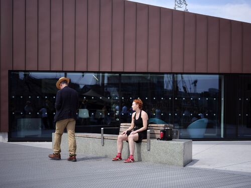 A woman on a bench watching a man passing by