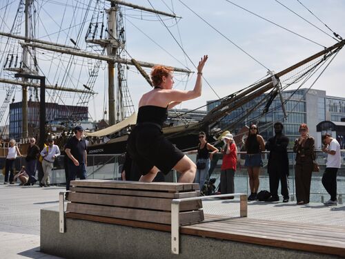 A dancer in a movement facing a ship