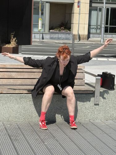 A dancer in a movement sitting on a bench