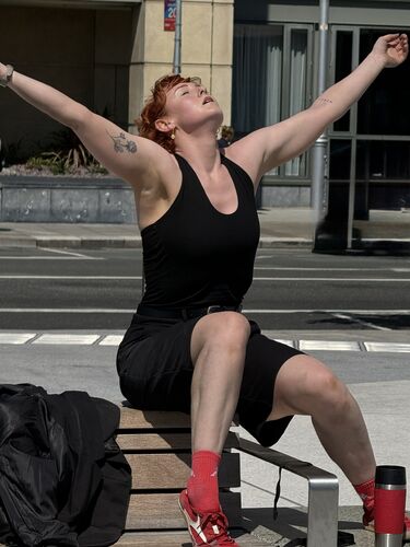 A dancer in a movement sitting on a bench