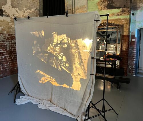 A projection of a car on a light fabric in the studio space