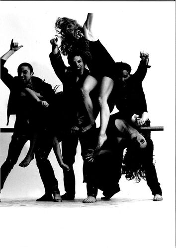 Black-and-white photo capturing group of dancers in a dynamic pose