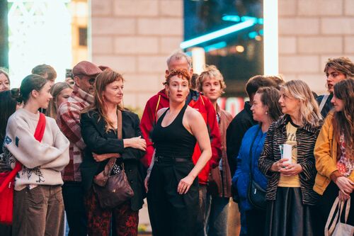 A dancer in a movement surrounded by spectators at the city centre square