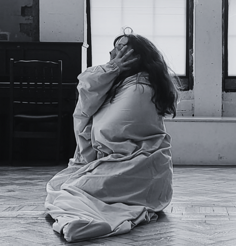 A woman sitting on her knees and covering her head with her arms